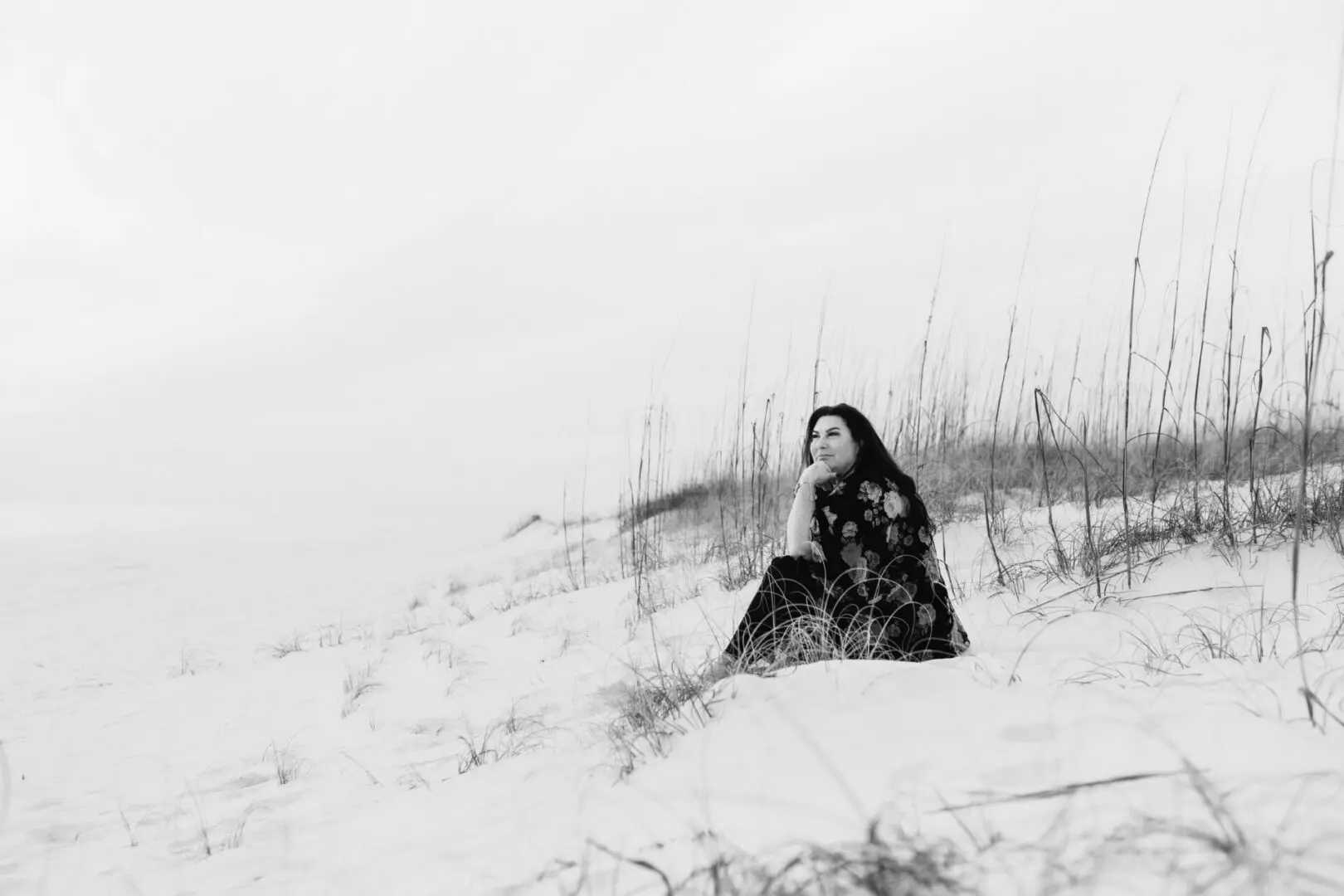 A woman sitting in the snow on top of a hill.